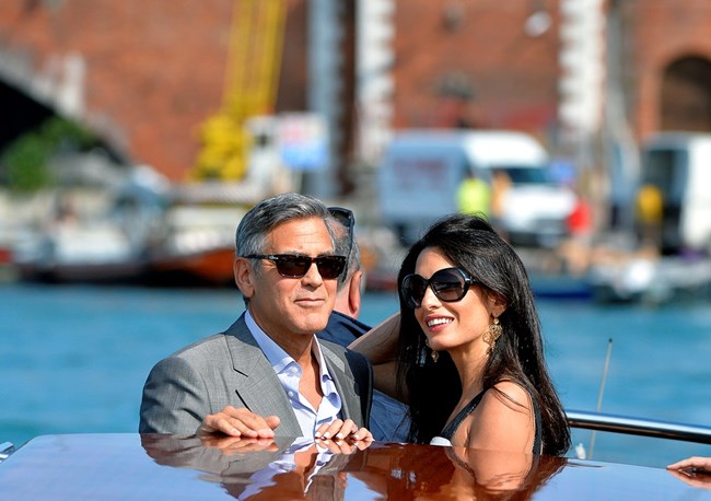 US actor George Clooney (L) and his Lebanon-born British fiancee Amal Alamuddin take a taxiboat upon their arrival in Venice on September 26, 2014, on the eve of their wedding.    AFP PHOTO / ANDREAS SOLARO